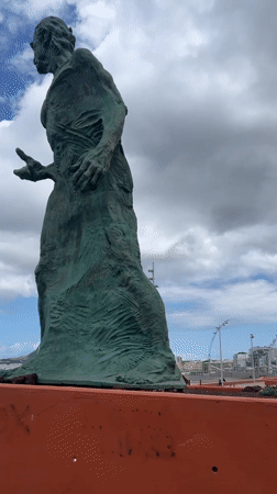 Tourists document statue, coastline during afternoon in Las Palmas