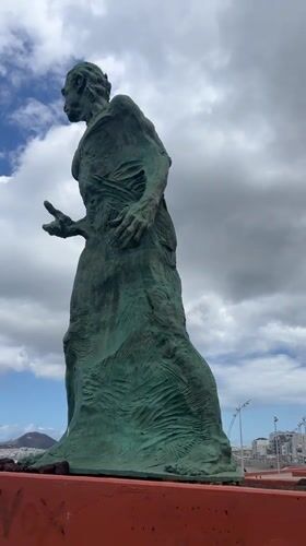 Tourists document statue, coastline during afternoon in Las Palmas