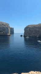 Exploring Dwejra Bay's cliffs, boats, and rocky coastline in Gozo