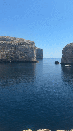 Exploring Dwejra Bay's cliffs, boats, and rocky coastline in Gozo