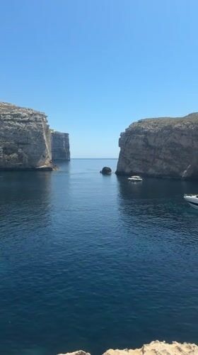 Exploring Dwejra Bay's cliffs, boats, and rocky coastline in Gozo