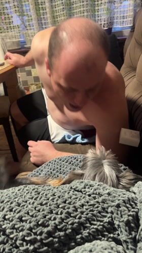 Man pets dog on couch in Bulgarian home