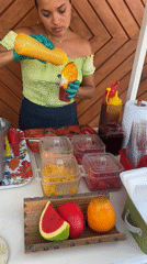 Woman prepares fruit refreshments at outdoor stand