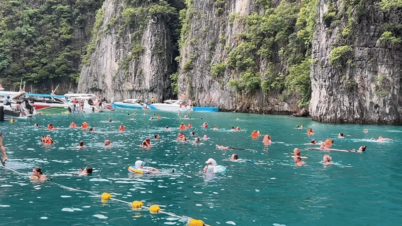 Swimmers and tour boats in Ao Nang's limestone-cliff bay