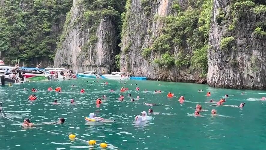 Swimmers and tour boats in Ao Nang's limestone-cliff bay
