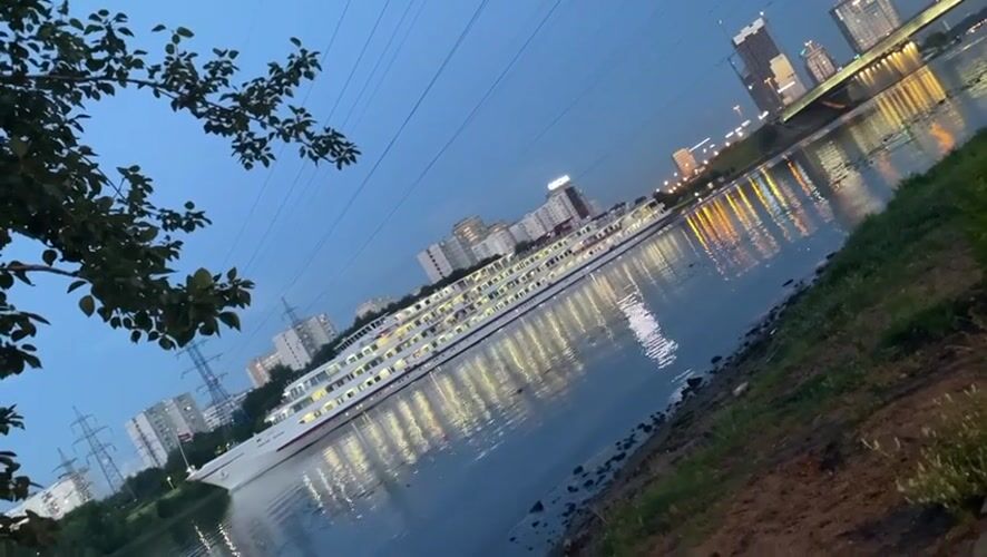 Dusk on the Moscow Canal: docked ship, city lights, waterfront path