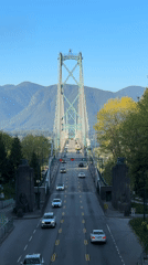 Late night traffic crosses Vancouver suspension bridge with mountain backdrop