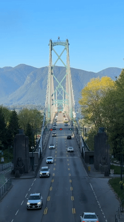 Late night traffic crosses Vancouver suspension bridge with mountain backdrop