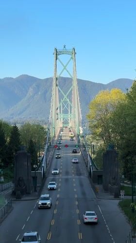 Late night traffic crosses Vancouver suspension bridge with mountain backdrop