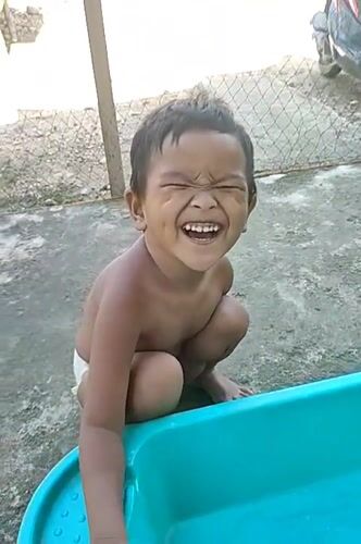 Playful moment by a teal bathtub in Indonesia