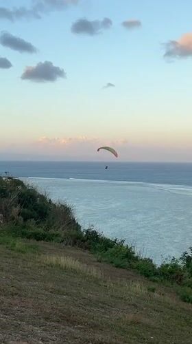 Paragliding over the Bali coast with a soccer match alongside