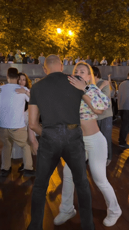Couples dancing on a Moscow riverside promenade at midsummer dusk