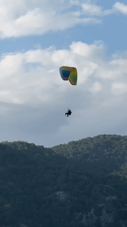 Paragliders spotted over forested mountains in Fethiye, Turkey