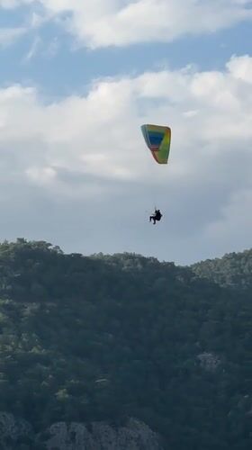 Paragliders spotted over forested mountains in Fethiye, Turkey