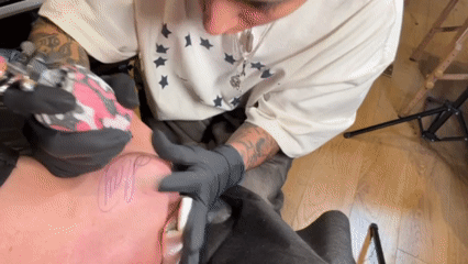 Tattoo artist works on client's arm in Los Angeles