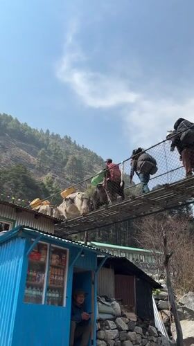 Trekkers cross suspension bridges over glacial rivers in Khumjung