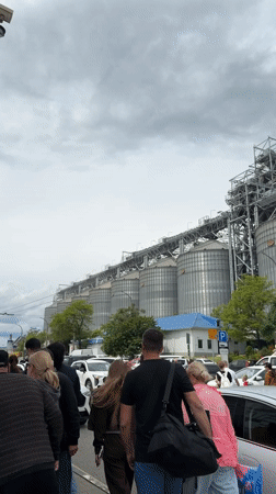 Crowds with luggage walk past grain silos in Novorossiysk
