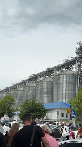 Crowds with luggage walk past grain silos in Novorossiysk