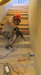 Man chips concrete step with power drill in Ramat HaSharon