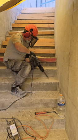 Man chips concrete step with power drill in Ramat HaSharon