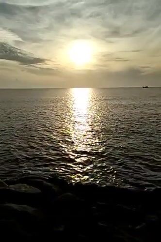 Golden hour on the Lhokseumawe coast, boats on the horizon