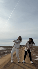 Two women dance on dirt road in Van'ki, Russia