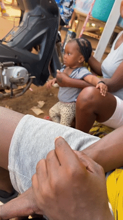 Woman holds baby and Guinness can in Kurunduma, Nigeria