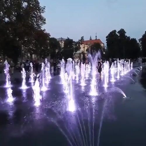 Purple-lit fountain glows in a Lviv square at dusk