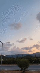 Sunset scene captured along foliage-lined road with hills backdrop