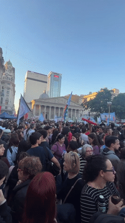 Crowd gathers with signs, flags in Buenos Aires square