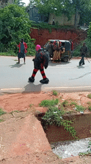 Traditional masquerade performer walks road as group gathers nearby