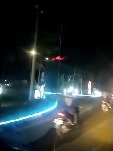 Evening traffic flows through illuminated Banda Aceh street