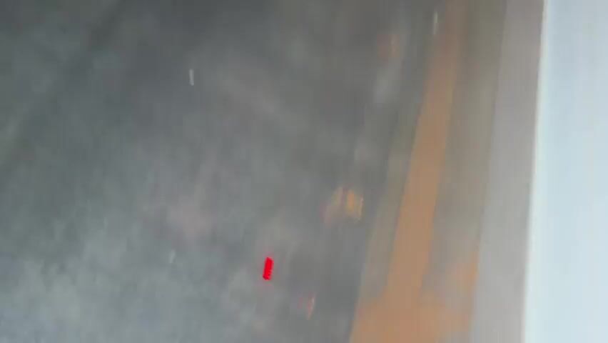 The video presents a highly abstract and blurry sequence, dominated by light patterns and rapid camera movement. It begins with a relatively static, out-of-focus shot featuring a vertical arrangement of seven small red dots, with a curved orange line positioned below them against a dark, indistinct background. This initial imagery suggests a display, a light fixture, or a reflection.

Following this, the camera rapidly moves and shakes, creating significant motion blur. The scene transitions to an extremely indistinct, dark environment, where blurry streaks and flashes of red and white lights are visible. The fast-paced and unsteady footage prevents the identification of specific objects, subjects, or detailed surroundings. The constant motion and blur suggest the video was recorded from a camera that was moving very quickly, possibly within a vehicle or during a rapid pass through an area.

The setting appears to be dark, implying either an indoor environment with low illumination or an outdoor night scene. No discernible people are visible, and there are no clear location cues beyond the general impression of movement through an undefined space. No visible text is present. The video maintains its abstract, blurry character with continuous rapid motion until its conclusion.