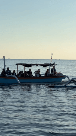 Traditional boats on calm Indonesian waters, mountains in the distance