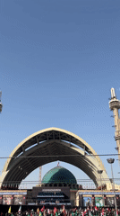 Religious gathering outside Tehran mosque with flags and ceremonial banners
