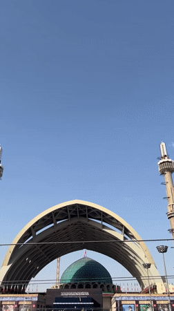 Religious gathering outside Tehran mosque with flags and ceremonial banners
