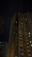 Kyiv apartment building at night, mostly dark with scattered lit windows