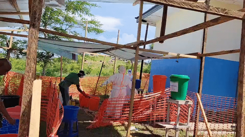 Health workers run outdoor decontamination stations in Tchere, DRC