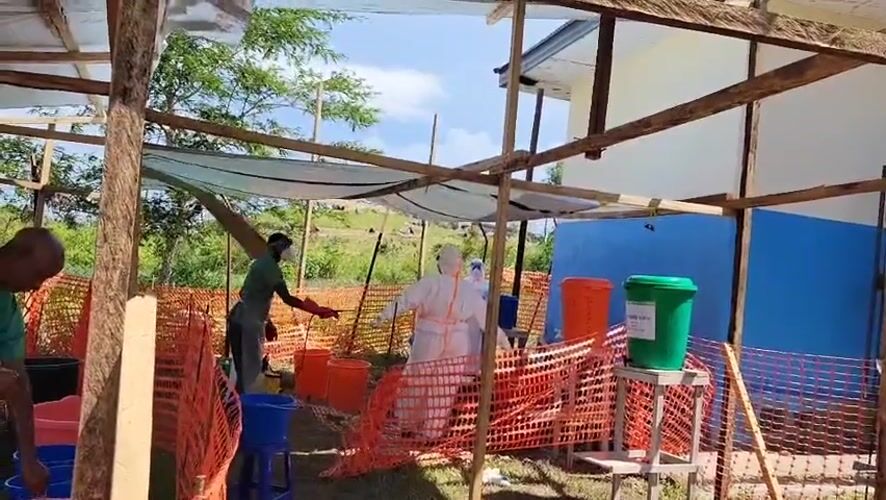 Health workers run outdoor decontamination stations in Tchere, DRC