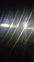 Nighttime airplane window view shows wing, ground lights