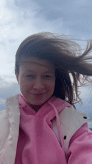 Woman enjoys windy day by water in Chaikovsky