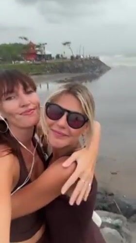 Two women take selfies with pug in Bali beach area