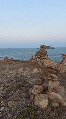Rock cairns dot Mui Ne coastline during sunset