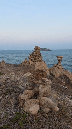 Rock cairns dot Mui Ne coastline during sunset