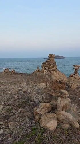 Rock cairns dot Mui Ne coastline during sunset