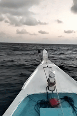 Boat navigates choppy Indonesian waters at dawn, towing unknown object