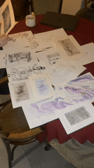 Person reviews sketches and drawings at cluttered Moscow table
