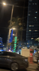 Nighttime vehicle journey through illuminated commercial city district documented