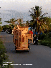 Motorcycle transports large wooden furniture structure through Lhokseumawe streets