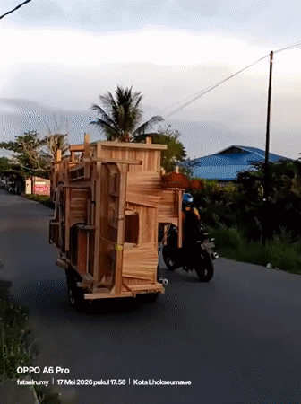 Motorcycle transports large wooden furniture structure through Lhokseumawe streets